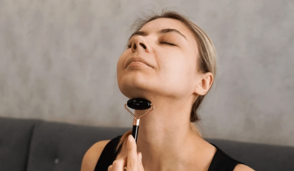 Woman using facial massage tool on neck area for wrinkles reduction exercise routine