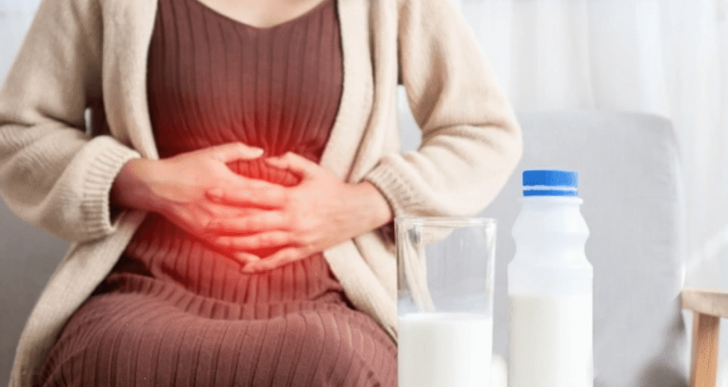 Woman experiencing lactose intolerance stomachache holding belly with milk glass and bottle nearby