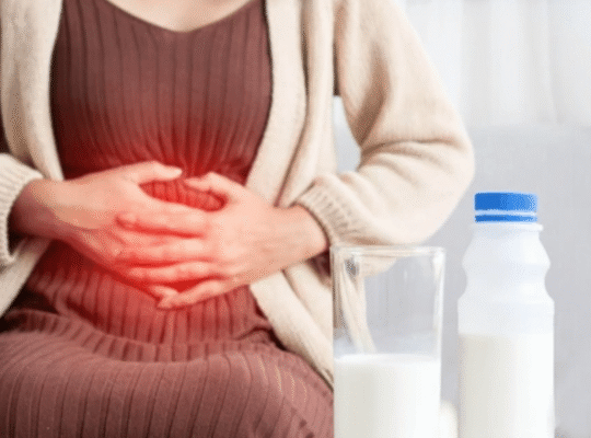 Woman experiencing lactose intolerance stomachache holding belly with milk glass and bottle nearby