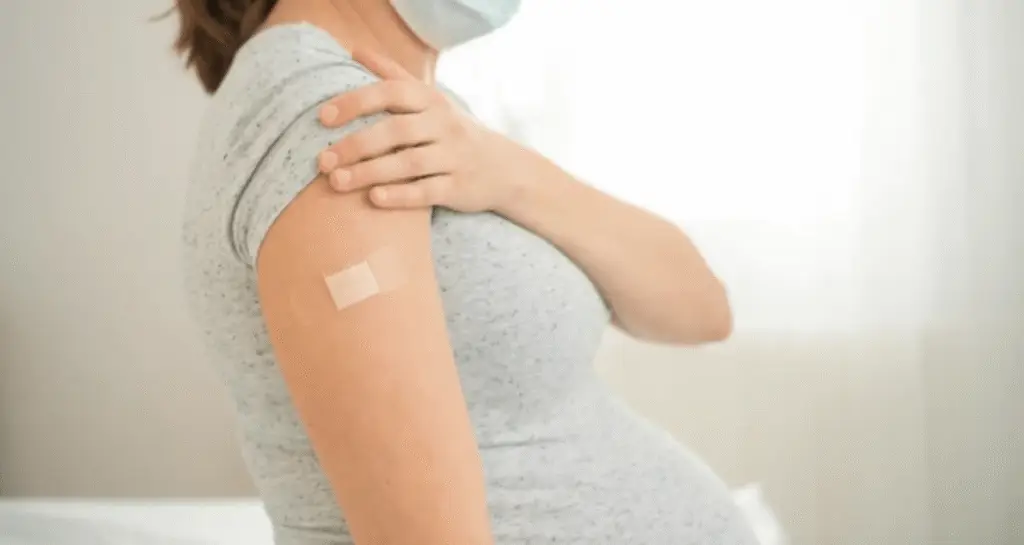 Pregnant woman wearing a mask after vaccination, supporting postpartum recovery and health after birth.