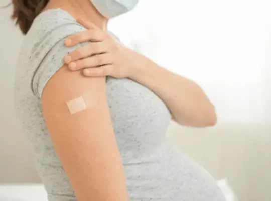 Pregnant woman wearing a mask after vaccination, supporting postpartum recovery and health after birth.