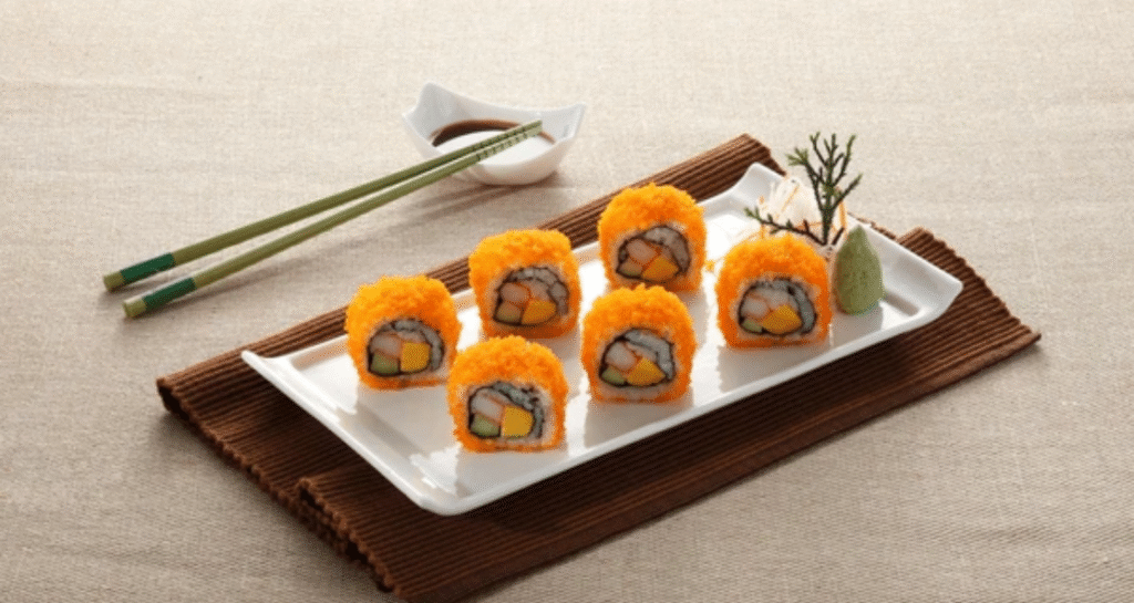Fresh masago capelin fish roe sushi rolls with orange coating served on white plate showcasing vibrant flavor and texture
