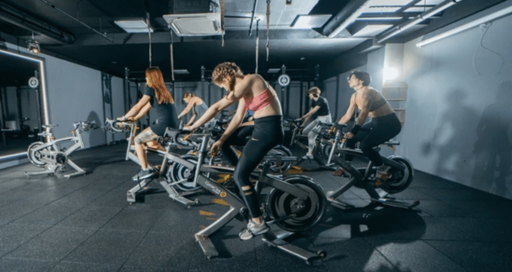 Group fitness class using spin bike equipment during intensive training session covering miles of indoor cycling