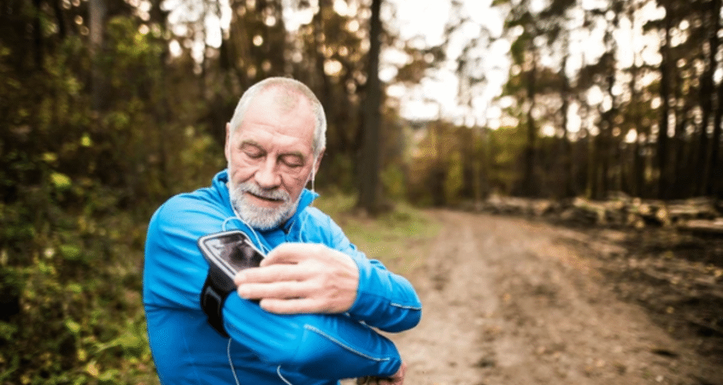 Senior runner checking MapMyRun accurate GPS tracking data on smartphone during outdoor forest trail running workout