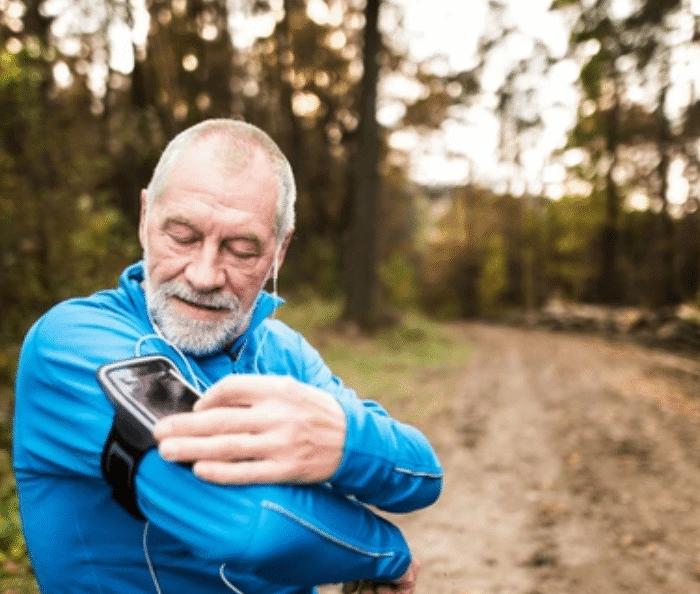 Senior runner checking MapMyRun accurate GPS tracking data on smartphone during outdoor forest trail running workout