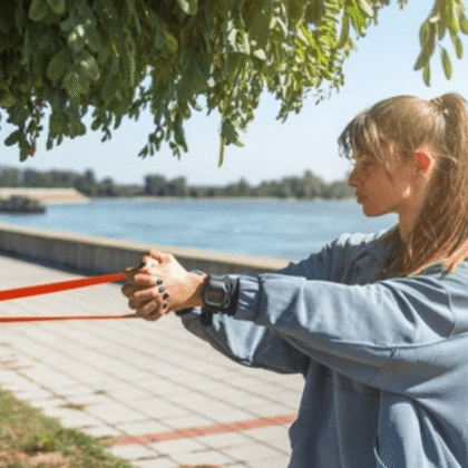 Woman performing resistance band exercises muscle atrophy recovery outdoors by waterfront