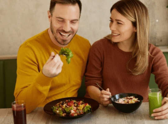 Happy couple eating healthy salads and drinking green smoothie at restaurant table
