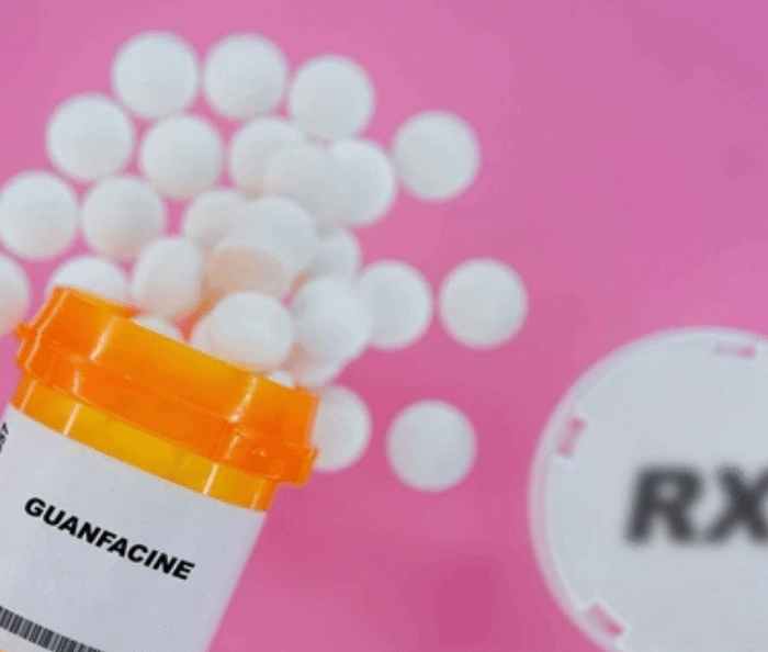 Guanfacine medication bottle with white pills and RX symbol showing ADHD treatment that may cause coughing in children