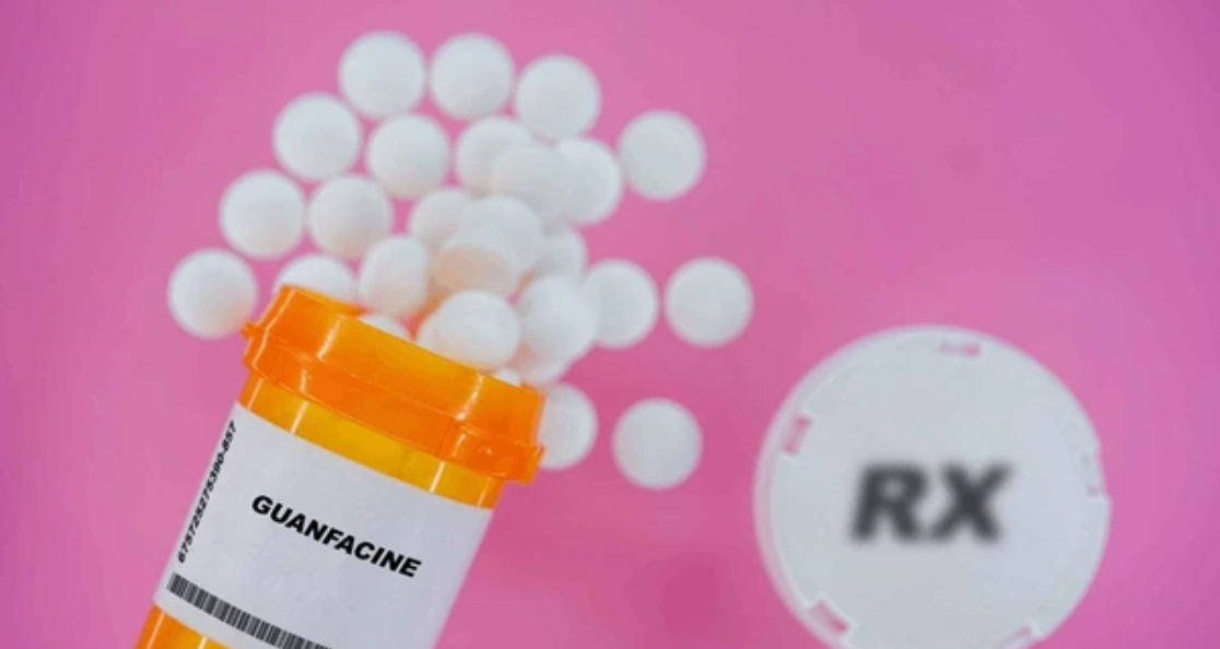 Guanfacine medication bottle with white pills and RX symbol showing ADHD treatment that may cause coughing in children