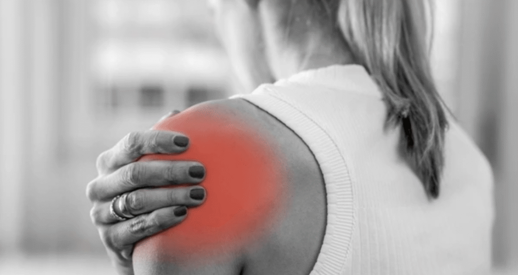 Woman experiencing shoulder pain holding inflamed area highlighted in red showing common joint injury and discomfort