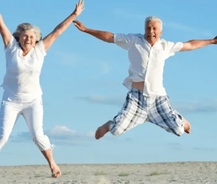 Active senior couple jumping joyfully on the beach, symbolizing the difference between healthspan and lifespan and how women can thrive longer, healthier lives.