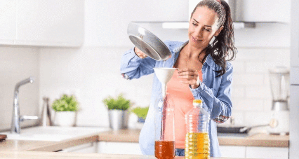 Woman safely filtering and storing cooking oil in glass containers in modern kitchen