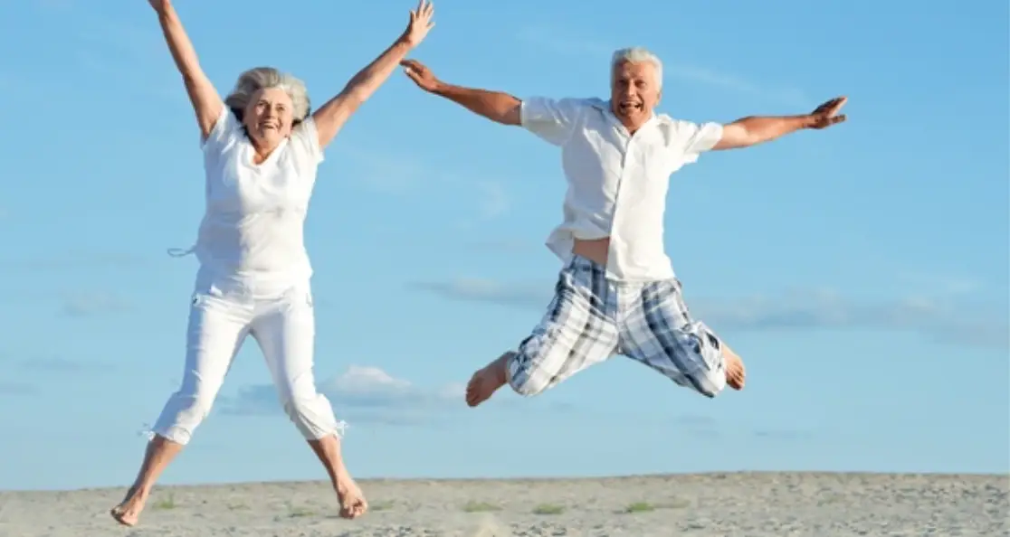 Active senior couple jumping joyfully on the beach, symbolizing the difference between healthspan and lifespan and how women can thrive longer, healthier lives.