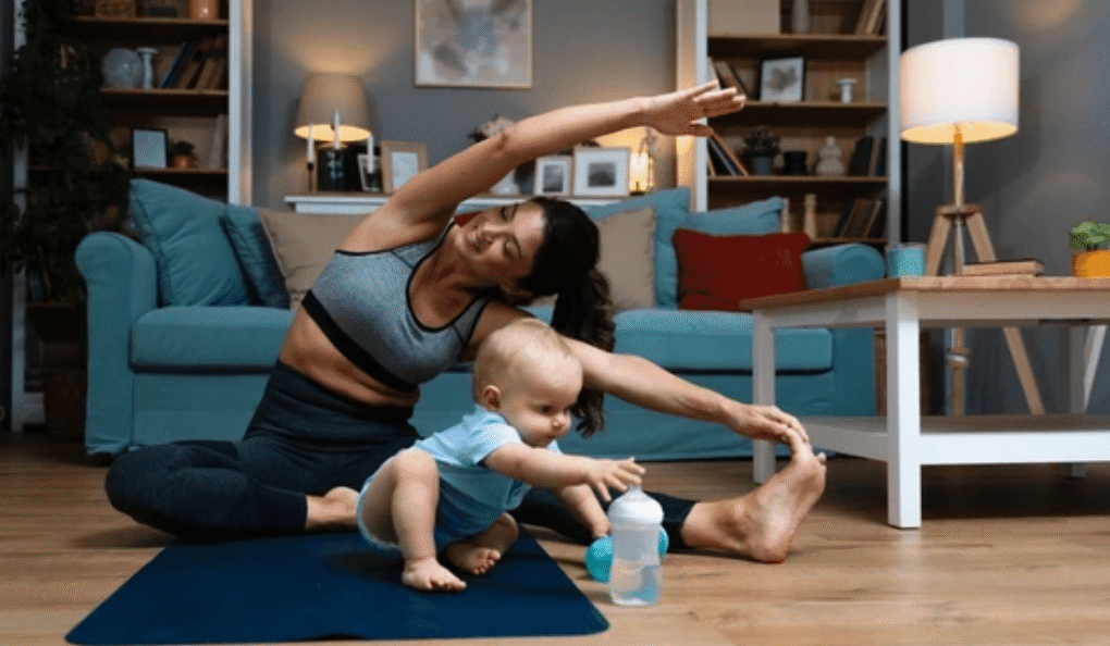 Woman doing postpartum yoga stretches with baby on exercise mat - postpartum weight loss tips for women