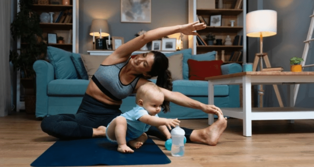 Woman doing postpartum yoga stretches with baby on exercise mat - postpartum weight loss tips for women