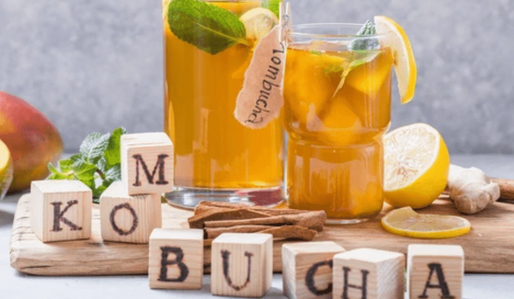 Kombucha drinks in glass jars with wooden blocks spelling KOMBUCHA - fermented tea that may help with bloating relief