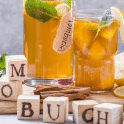 Kombucha drinks in glass jars with wooden blocks spelling KOMBUCHA - fermented tea that may help with bloating relief